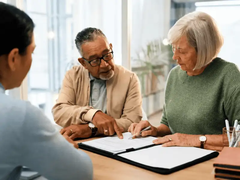 Seniors reviewing Medicare insurance documents with a trusted insurance advisor.